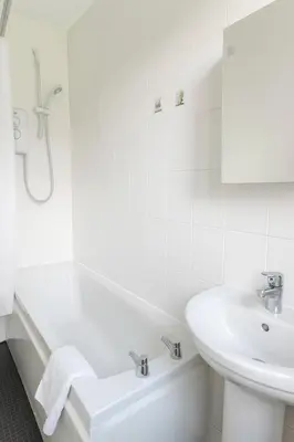 a white bathroom with a tub and a sink at Bright & Spacious 2 Bedroom Flat in Edinburgh