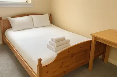 a bedroom with a wooden bed with towels on it at Bright & Spacious 2 Bedroom Flat in Edinburgh