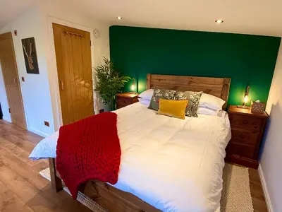 a bedroom with a large bed with a green wall at Stylish Cabin with Countryside Views and King Bed in Maybole