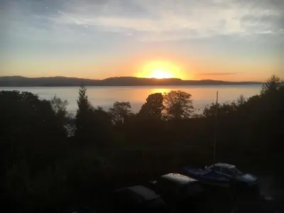 a sunset over a body of water with boats at A Baronial Hall apartment - great views of Loch Fyne