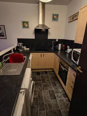 a kitchen with black counter tops and a red chair at A Baronial Hall apartment - great views of Loch Fyne