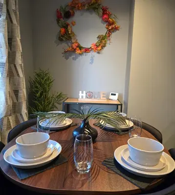 a wooden table with plates and bowls and a wreath at 3 Bedroom FM Homes & Apartments Wishaw Motherwell in Dalziel