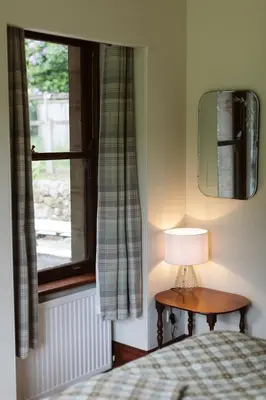 a bedroom with a bed and a lamp and a window at The Coach House in Castle Douglas