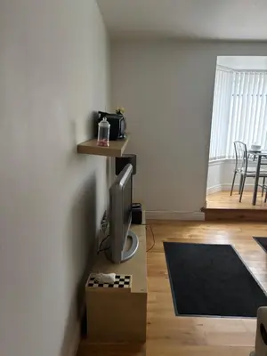 a living room with a television on a box at Thistle Tide 13 Nelson Street Largs KA308LN 1st Floor in Largs