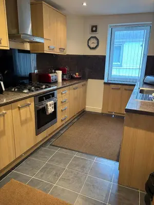 a kitchen with wooden cabinets and a stove and a window at Thistle Tide 13 Nelson Street Largs KA308LN 1st Floor in Largs