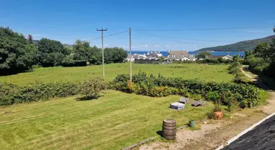 an aerial view of a green field with a house at Rock Cottage in Isle of Arran