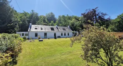 a large white house on a grass field at Rock Cottage in Isle of Arran