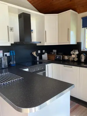 a kitchen with white cabinets and a black counter top at Golden Mary in Morenish