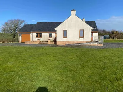 a house with a grass yard in front of it at Laggansally Lodge in Leswalt