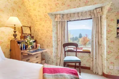a bedroom with a window and a desk with a chair at Glenogle Highland Estate Home in Lochearnhead