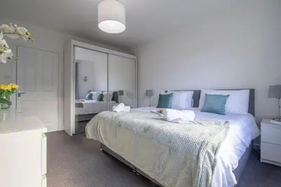 a white bedroom with a large bed and a mirror at Ashgrove House - 3 bedroom in Coatbridge