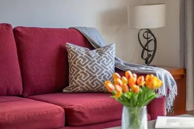 a red couch with a vase of flowers on a table at Ashgrove House - 3 bedroom in Coatbridge