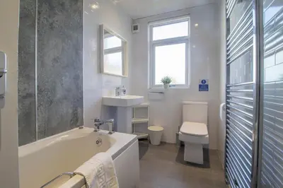 a bathroom with a tub and a toilet and a sink at Ashgrove House - 3 bedroom in Coatbridge