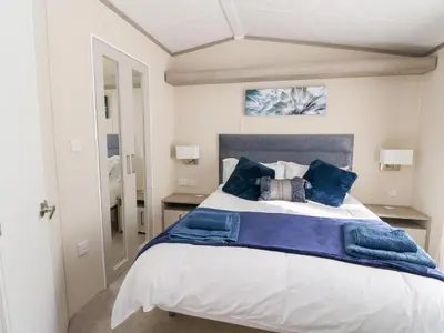 a bedroom with a large bed with blue pillows at Altair Lodge in Crieff