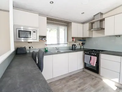 a kitchen with white cabinets and a sink and a stove at Altair Lodge in Crieff