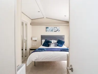 a bedroom with a large bed with blue pillows at Altair Lodge in Crieff