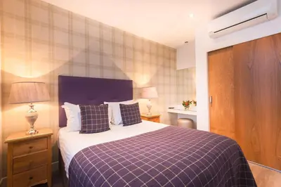 a bedroom with a bed with a blue and white blanket at Braid Apartments by Mansley in Edinburgh