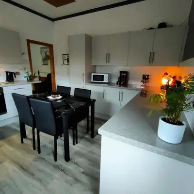 a kitchen with a table and black chairs in a room at The Old Smiddy Cottage and Apartment in Balloch