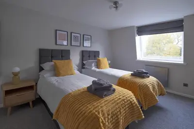 a bedroom with two beds with yellow sheets and a window at Park View apartment, Gleneagles Village, Auchterarder in Auchterarder