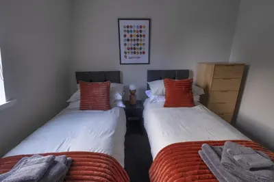 two beds in a room with red pillows on them at Park View apartment, Gleneagles Village, Auchterarder in Auchterarder