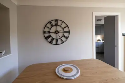 a clock on a wall with a plate on a table at Park View apartment, Gleneagles Village, Auchterarder in Auchterarder