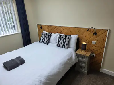 a bedroom with a white bed with a wooden headboard at Balnakeil house