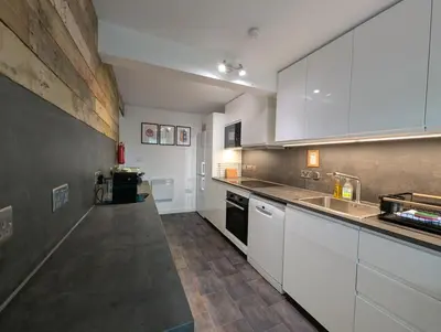 a large kitchen with white cabinets and a sink at Ashdale Cottage with Sauna, Plunge Pool, Games Room, Kit Drying Room in Isle of Arran