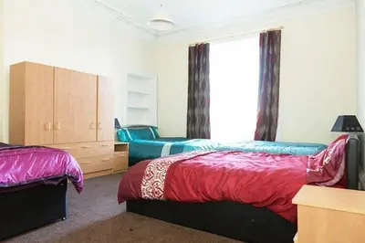 a bedroom with two beds and a large window at Edinburgh Central Lauriston Large Apartment in Edinburgh