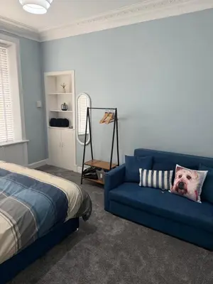a bedroom with a blue couch and a bed at Woodside Bungalow in Stevenston