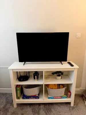 a tv on a white stand with a tv at Woodside Bungalow in Stevenston