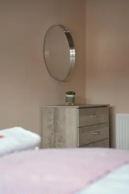 a bedroom with a dresser and a mirror on the wall at Beechgrove House in Livingston