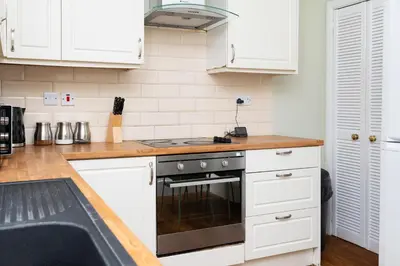 a kitchen with white cabinets and a stove top oven at 2Bed Upper Cottage-Street Parking-by Holiday Homes in Falkirk