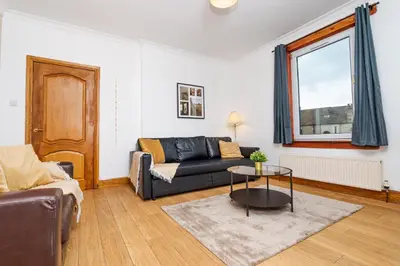 a living room with a couch and a table at 2Bed Upper Cottage-Street Parking-by Holiday Homes in Falkirk