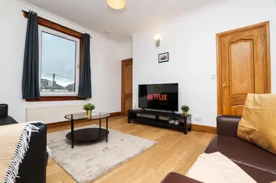 a living room with a couch and a tv at 2Bed Upper Cottage-Street Parking-by Holiday Homes in Falkirk