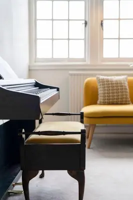 a living room with a piano and a yellow chair at GuestReady - Elegant Edinburgh Retreat in Edinburgh