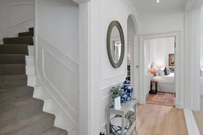 a white hallway with a staircase and a mirror at GuestReady - Elegant Edinburgh Retreat in Edinburgh