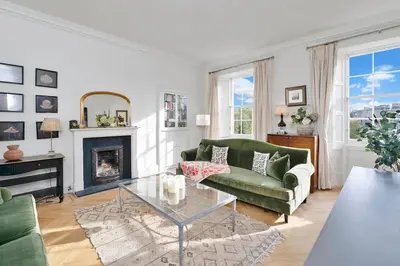 a living room with a green couch and a fireplace at GuestReady - Elegant Edinburgh Retreat in Edinburgh