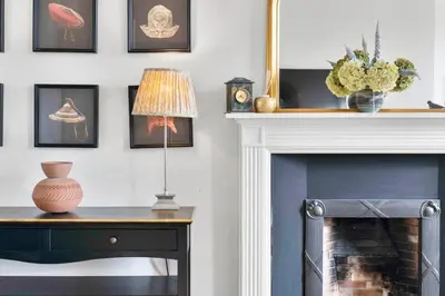 a room with a fireplace and a table with a lamp at GuestReady - Elegant Edinburgh Retreat in Edinburgh