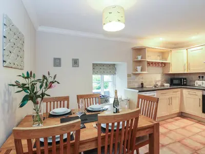 a kitchen and dining room with a wooden table and chairs at The Cottage in Perth