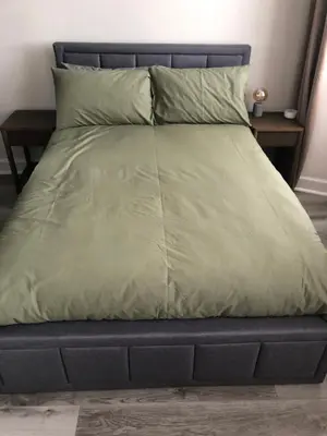 a bed with a green comforter and pillows at Charming West End Flat in Edinburgh