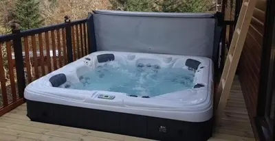 a hot tub sitting on a deck on a porch at Sòghail Luxury Lodge and Balquhidder Mhor with Hot Tub in Kingshouse