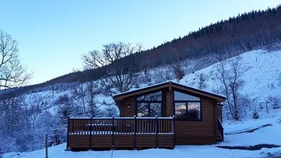 a cabin in the snow on a snowy hill at Sòghail Luxury Lodge and Balquhidder Mhor with Hot Tub in Kingshouse