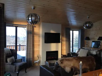 a living room with a couch and a fireplace at Sòghail Luxury Lodge and Balquhidder Mhor with Hot Tub in Kingshouse