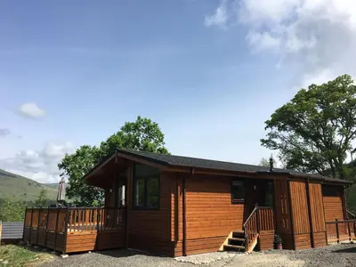 a log cabin with a porch and a deck at Sòghail Luxury Lodge and Balquhidder Mhor with Hot Tub in Kingshouse