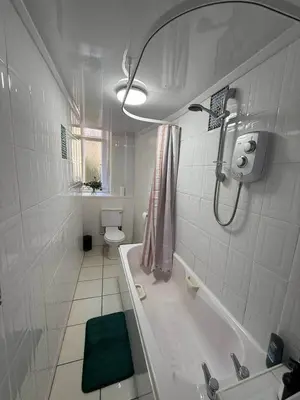 a white bathroom with a tub and a toilet at 2BR Flat with Parking Near Glasgow Green and Parks in Glasgow