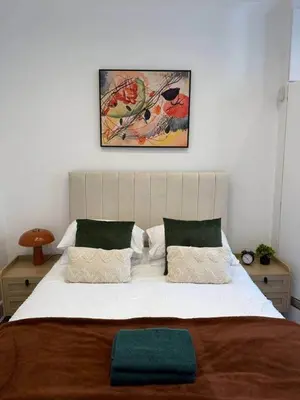 a bed in a bedroom with a picture on the wall at 2BR Flat with Parking Near Glasgow Green and Parks in Glasgow