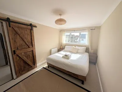 a bedroom with a bed and a sliding barn door at Newly Refurbished 3 Bed House with 2-Sided Wood Burner and Garden in Edinburgh in Edinburgh