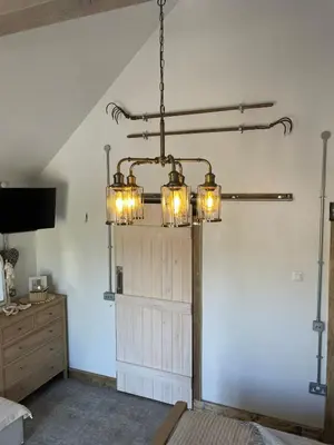 a chandelier in a room with a barn door at Pink Cottage in Kirkcowan