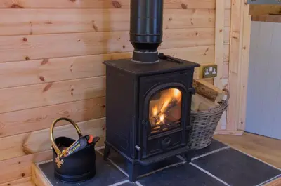 a black stove in a room with a basket at Wildcat Lodge in Kilmichael Glassary