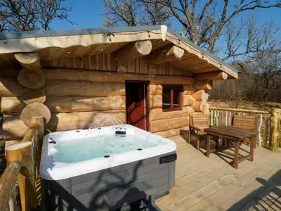 a wooden cabin with a hot tub on a deck at Pine Marten in Kilmichael Glassary